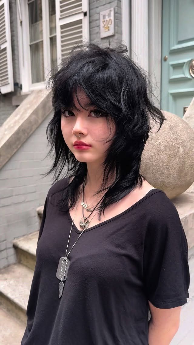 Young woman showing a shaggy layered black wolf cut with loose waves