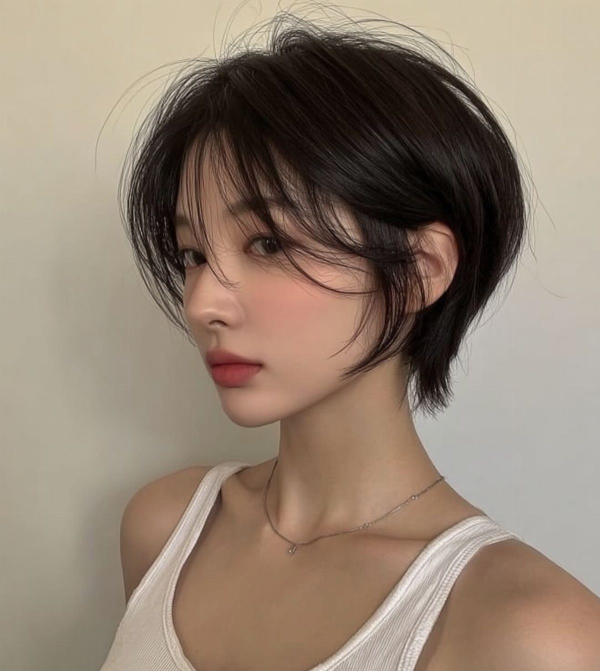 Short tousled dark pixie bob with long wispy bangs and layered ends