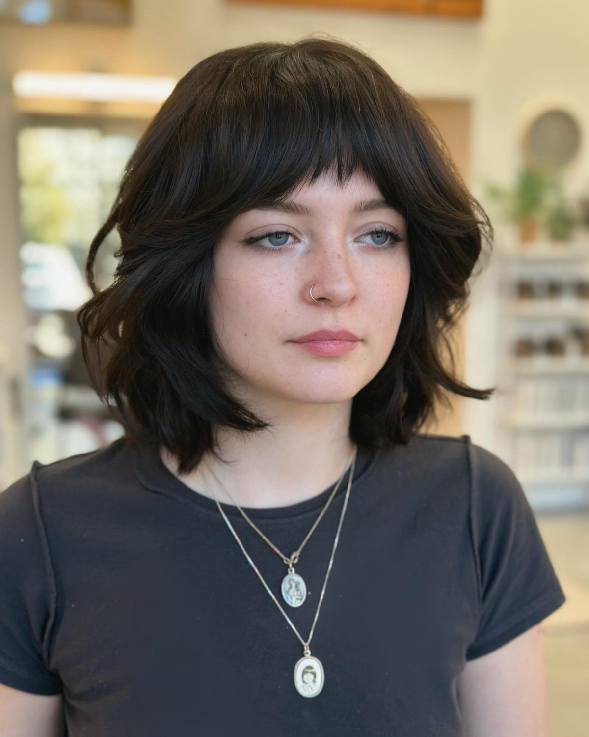Woman with a short dark shag haircut and wispy bangs