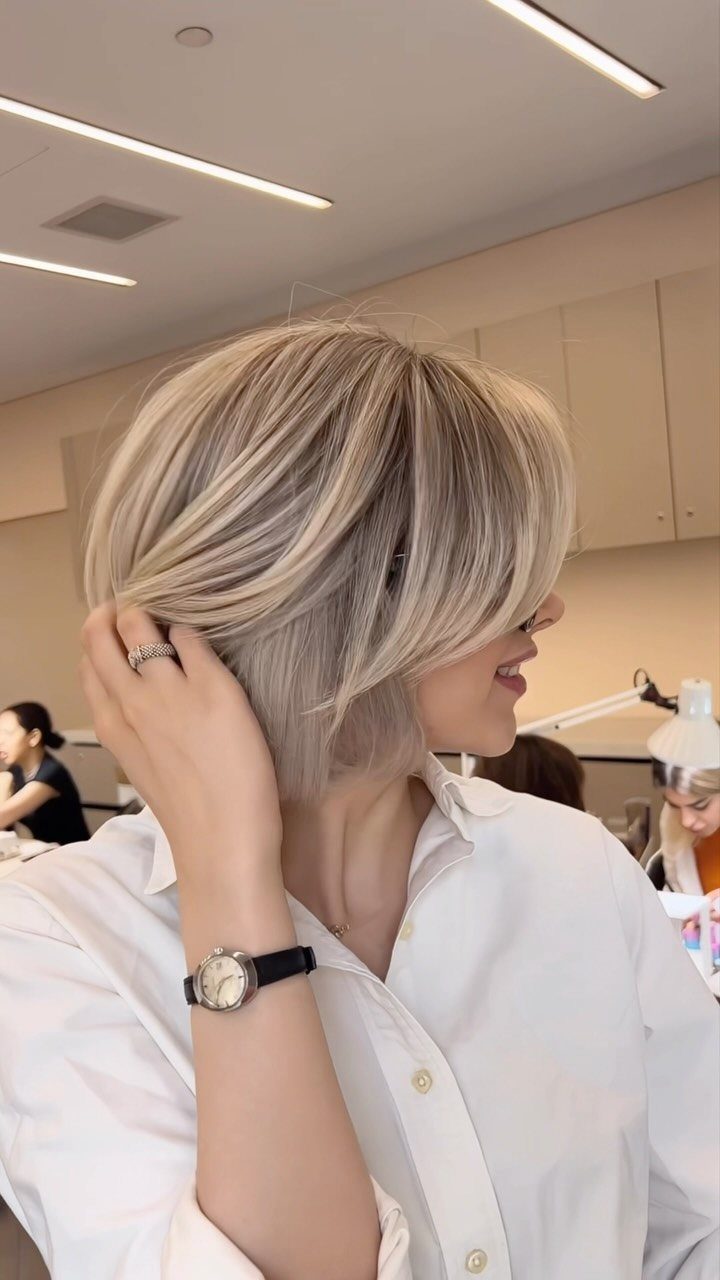 Woman displaying a tousled highlighted silver-blonde layered bob in a salon