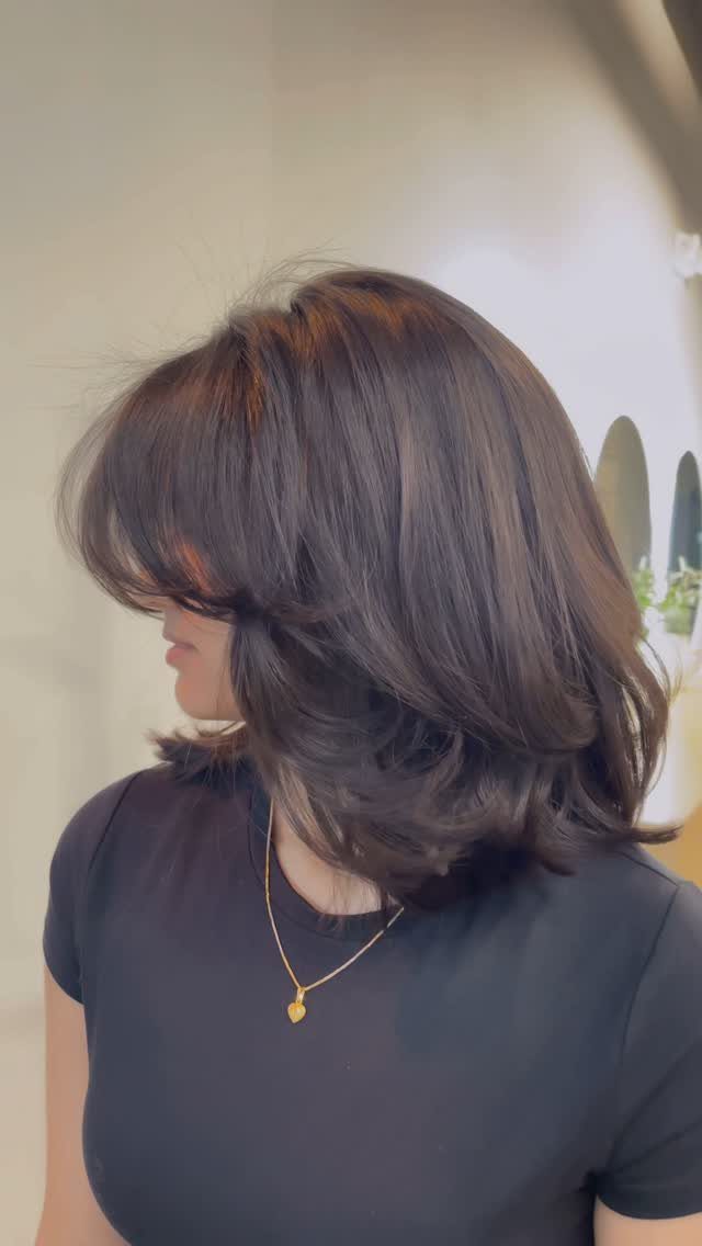 Shoulder-length dark hair with voluminous ’90s layers framing the face