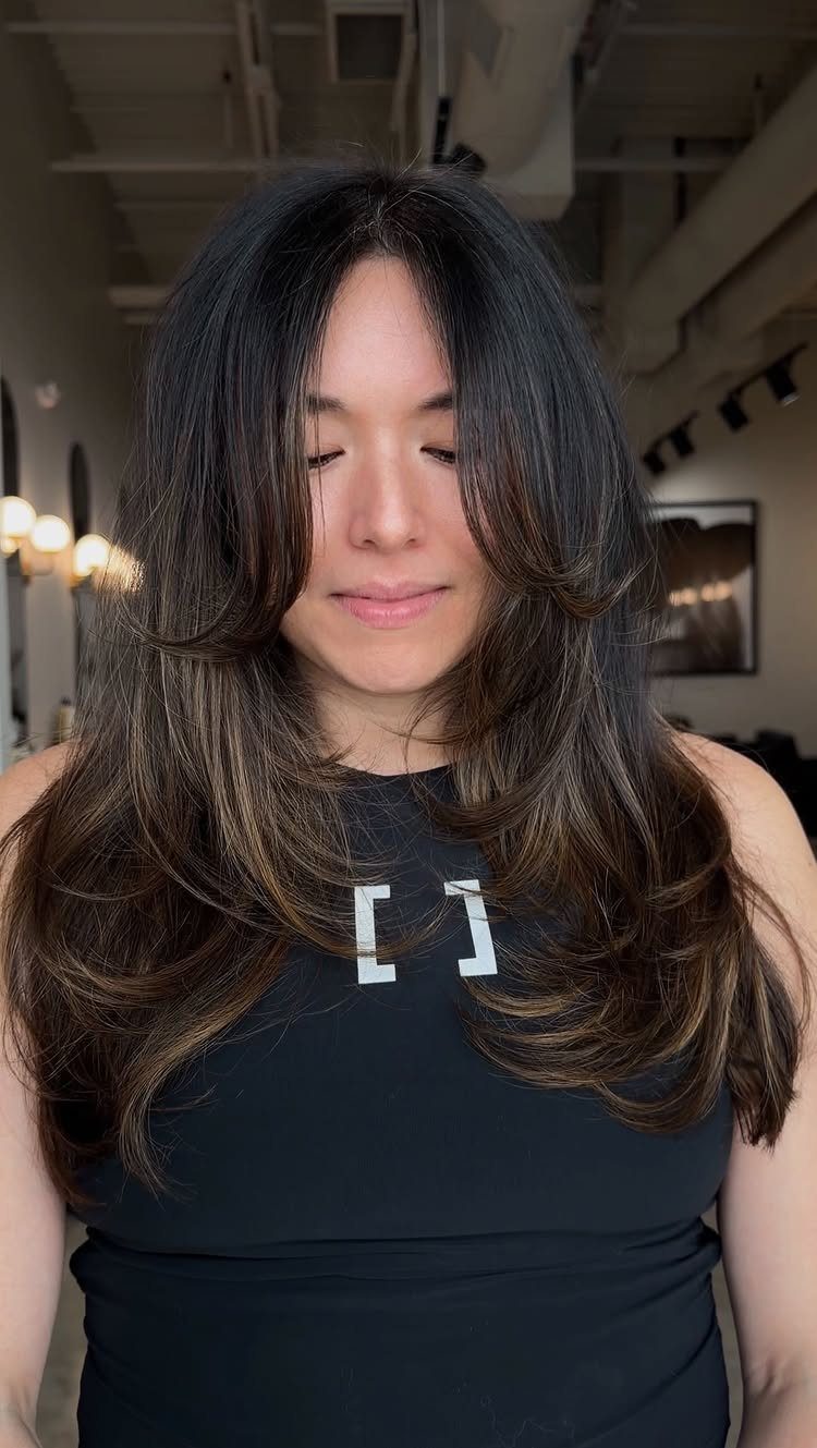 Dark layered hair curves around the face and falls in soft waves