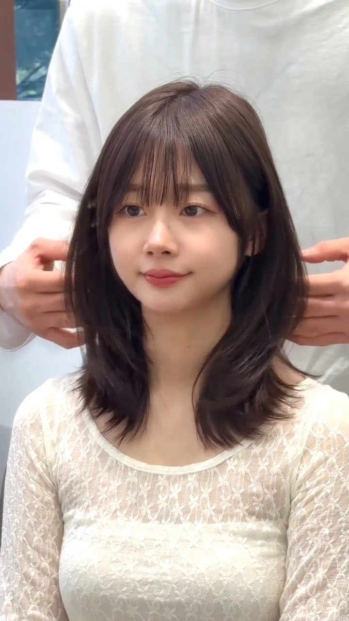 Woman with shoulder-length layered hair and wispy face-framing bangs