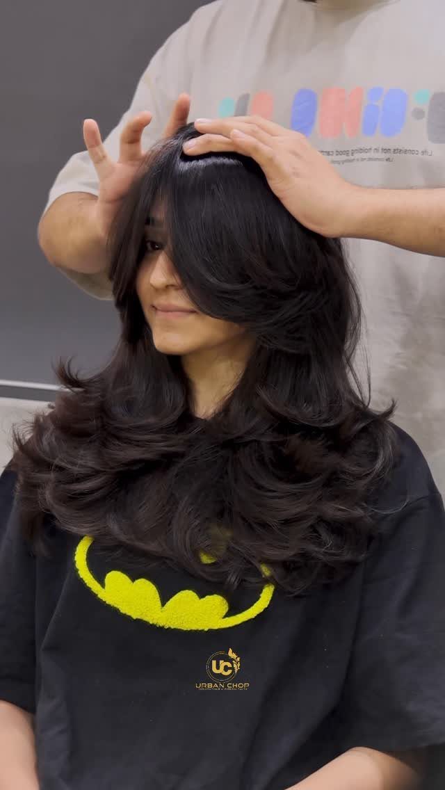 Dark shoulder-length feathered layers with sweeping bangs styled in a salon
