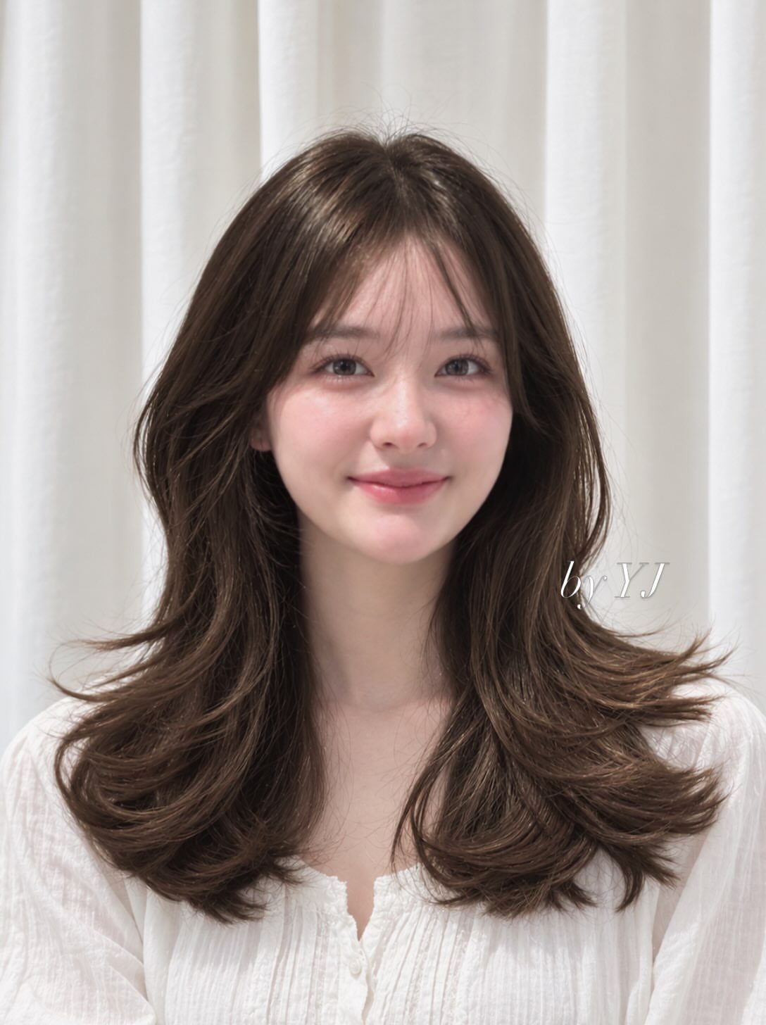 Woman with dark layered hair and wispy bangs, ends flicked outward