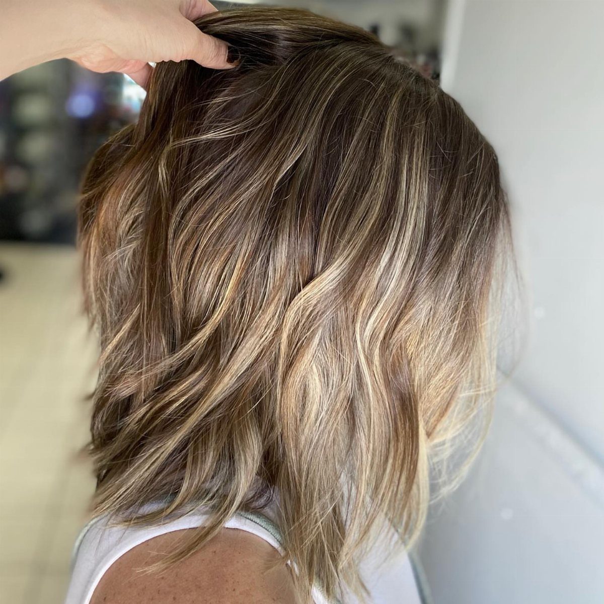 Wavy medium-length brown and blonde lob with layered balayage highlights