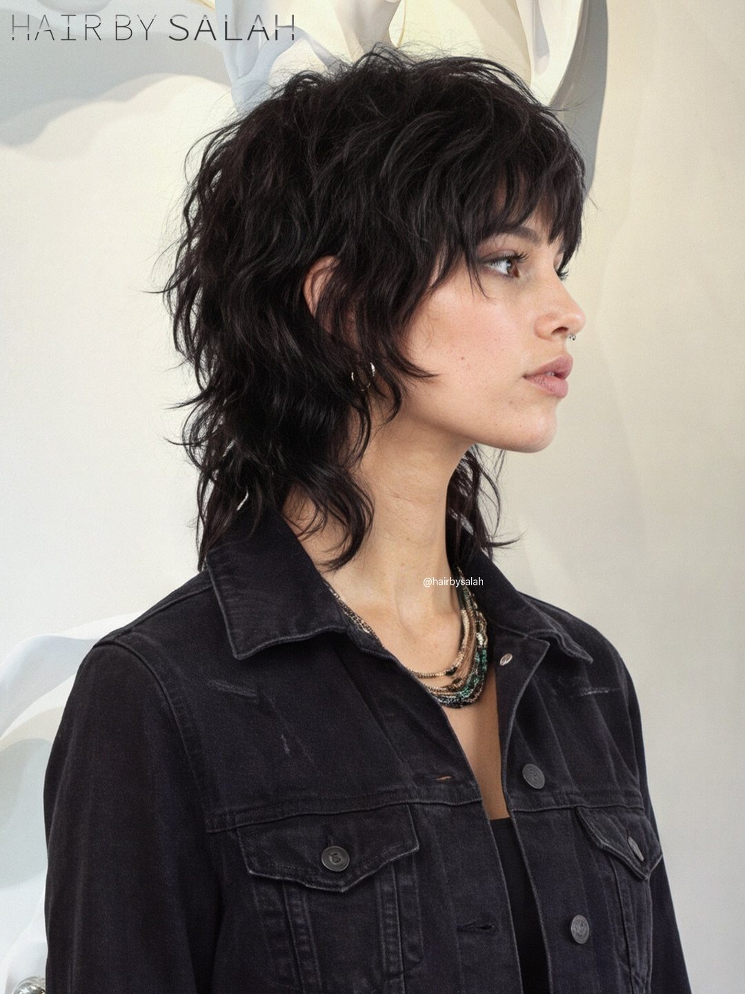 Woman with a tousled dark shoulder-length shag haircut and choppy bangs