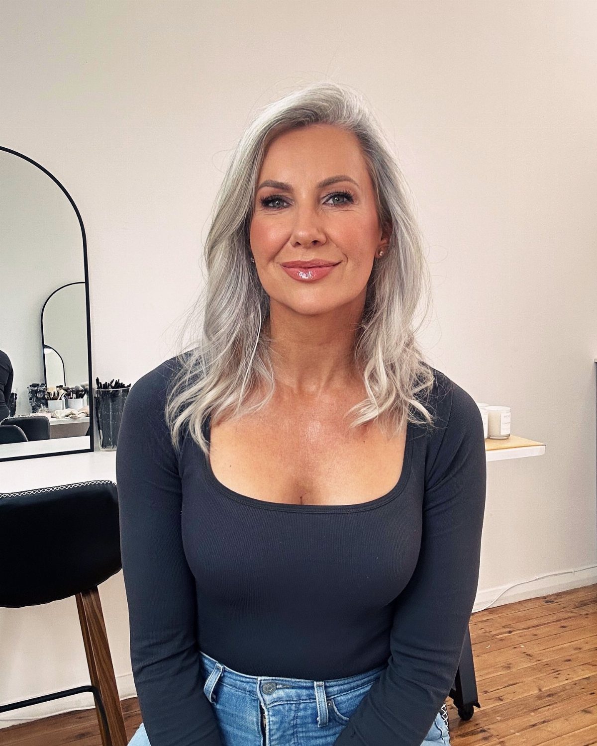 Woman with silver-grey layered hair seated in a bright salon