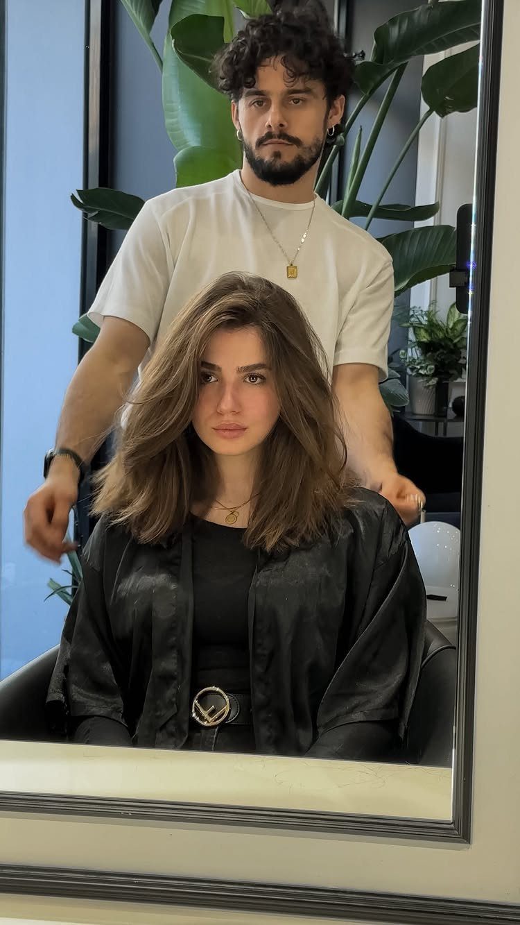 Woman with softly layered shoulder-length hair seated in a salon chair