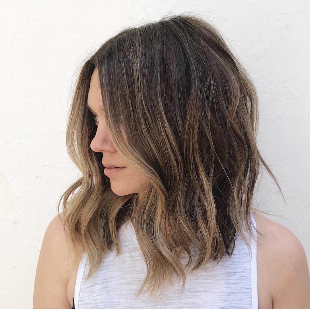 Woman showing a wavy brown shoulder-length lob with honey-toned ends