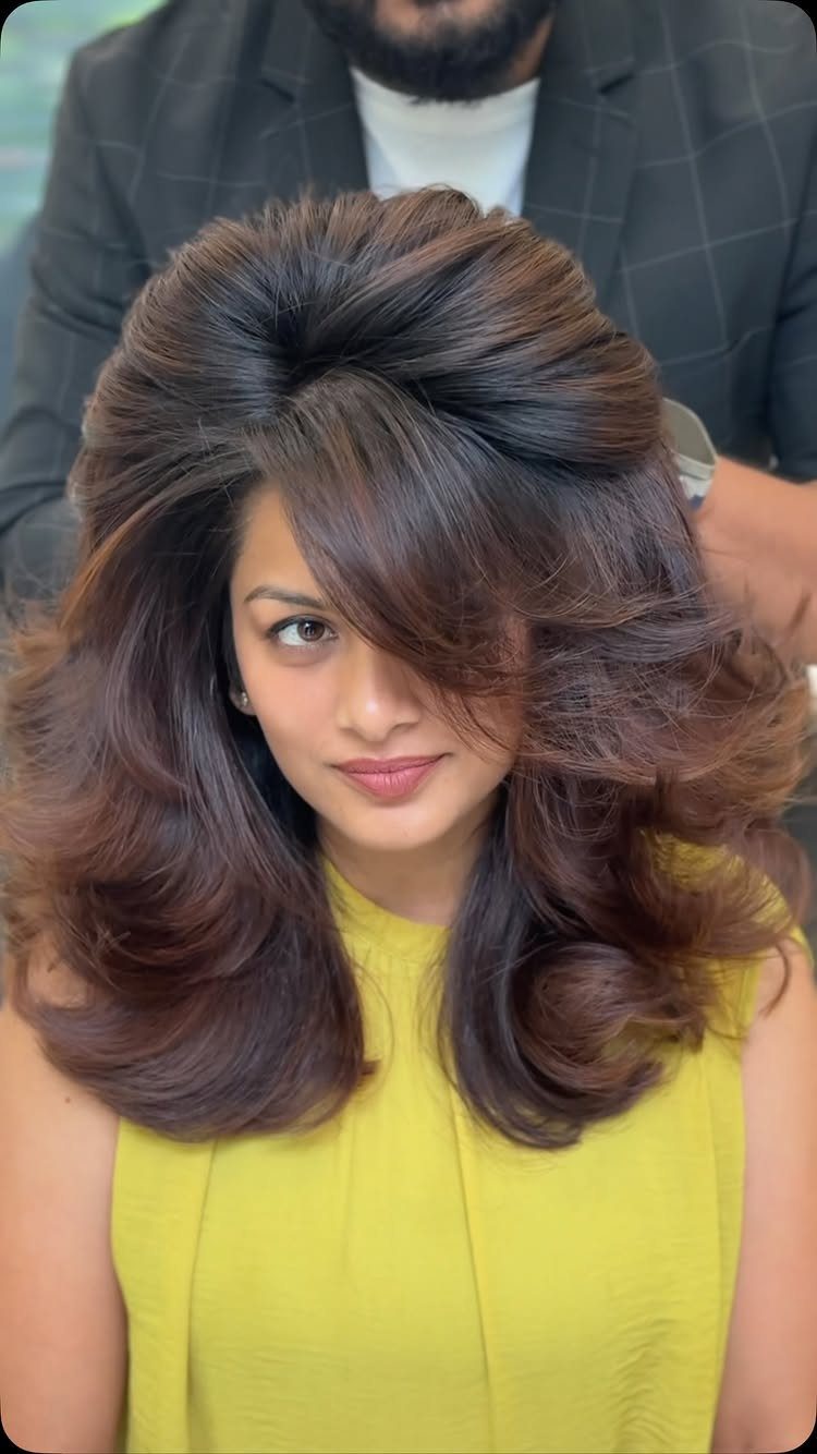 Woman with voluminous brunette layers curled outward around her face and shoulders