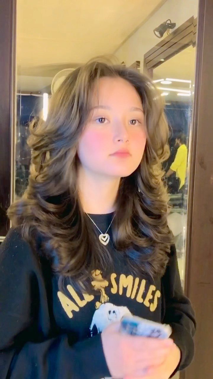 Person with dark layered hair curled into voluminous outward-flipped ends