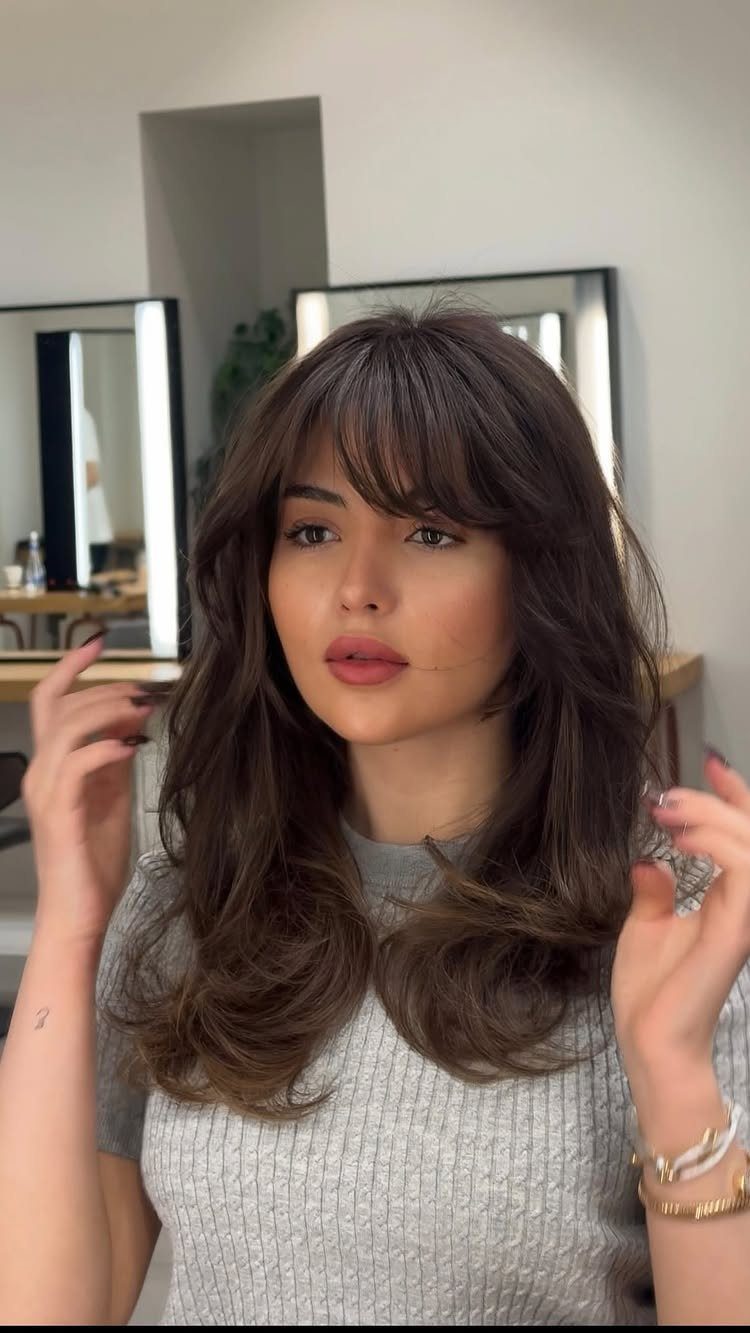 Woman showing dark layered hair with choppy face-framing bangs