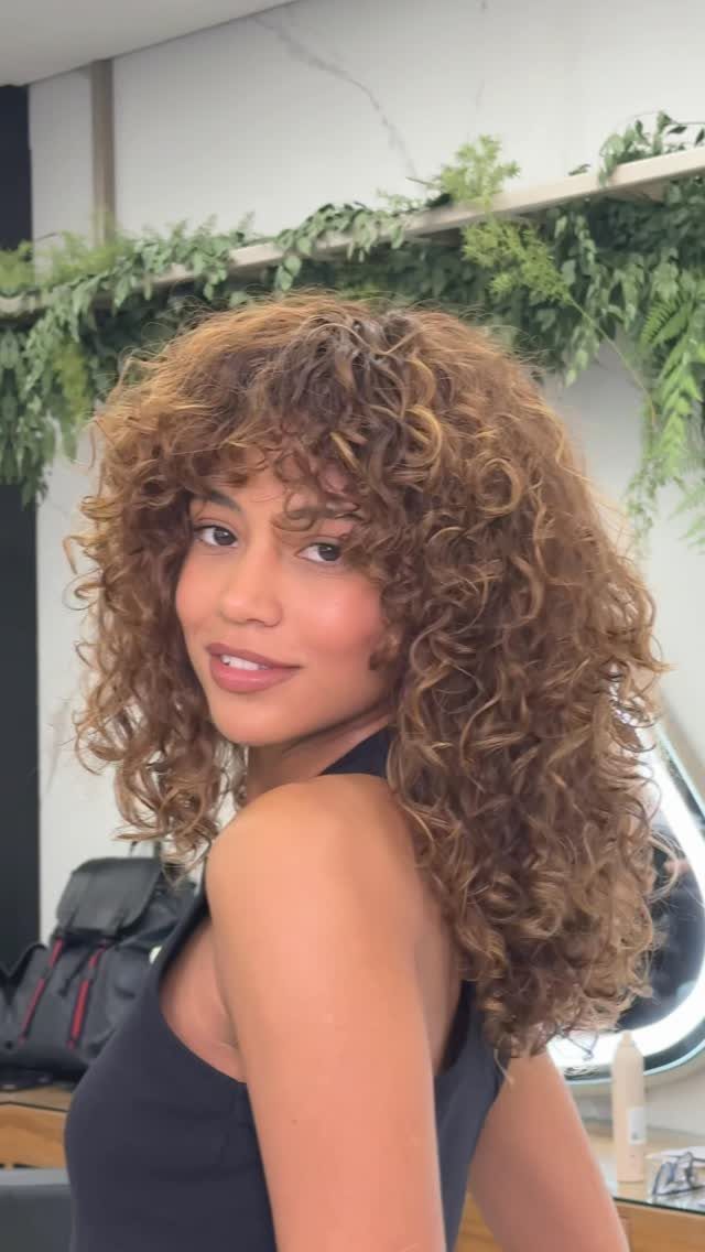 Woman showing voluminous layered auburn curls in a salon