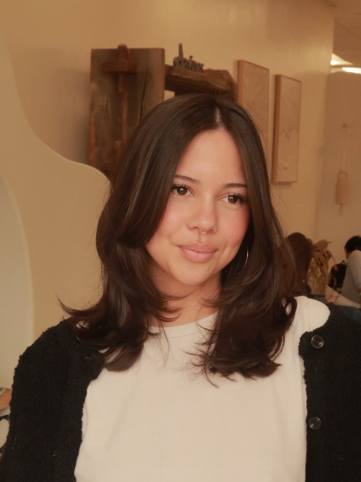 Woman with long dark layered hair and curled ends posing indoors