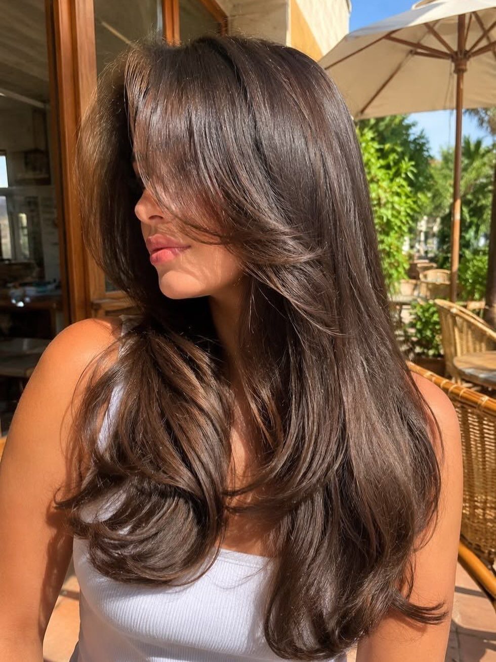 Woman with glossy dark brown hair styled in tousled tapered layers