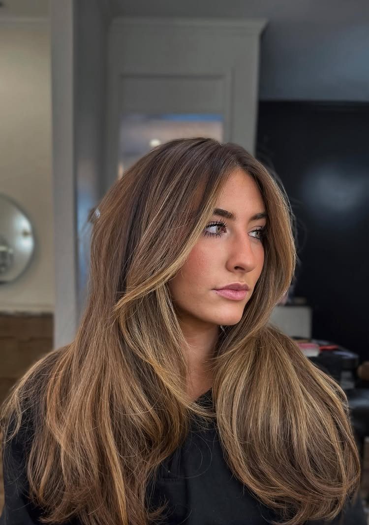 Woman showing long light brown hair with blonde balayage highlights and loose waves