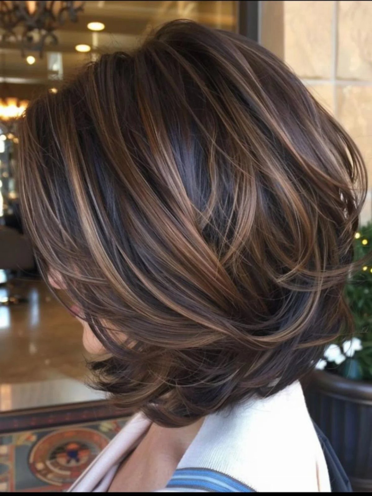 Choppy brown bob with sweeping caramel-blonde highlights and layered ends
