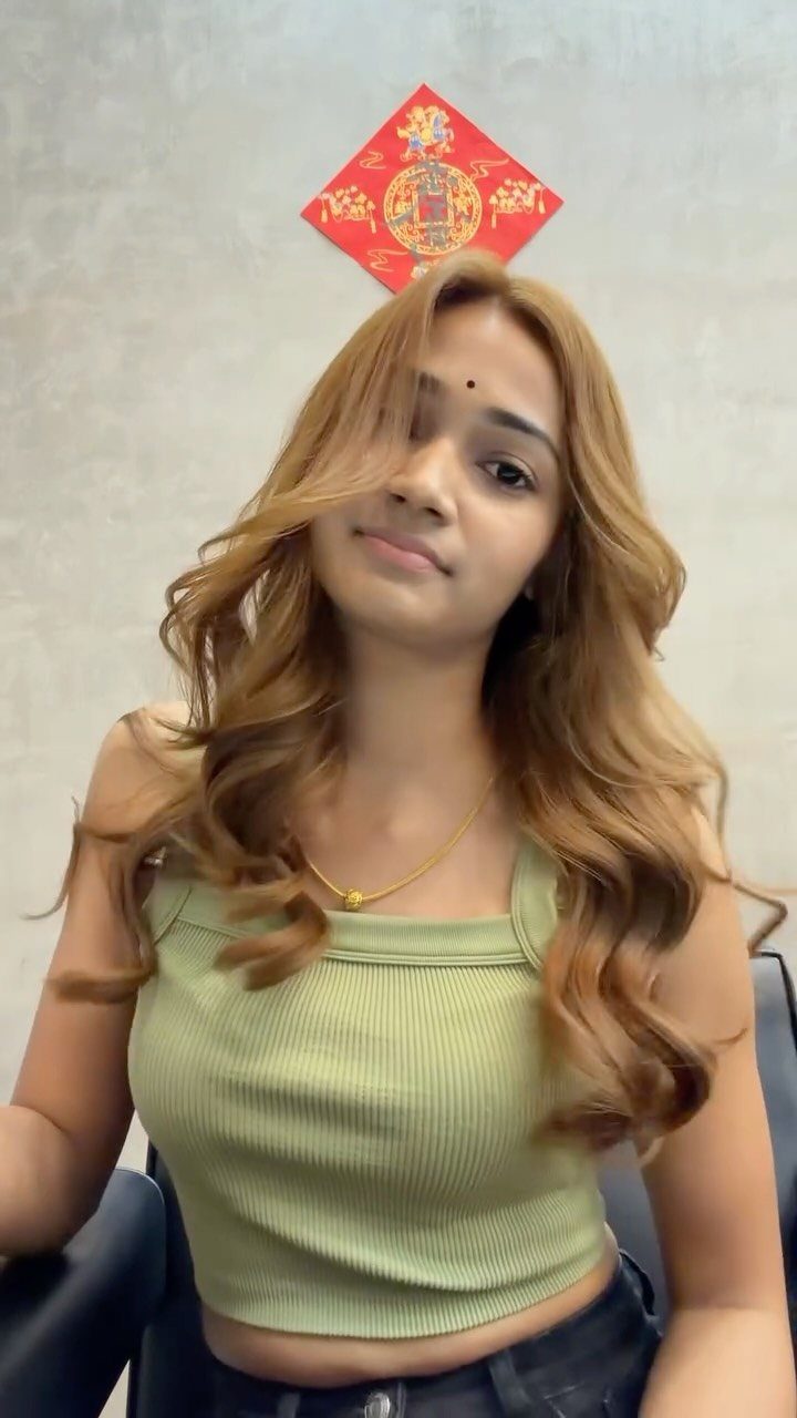 Woman displaying long wavy caramel brown hair with warm dimensional tones