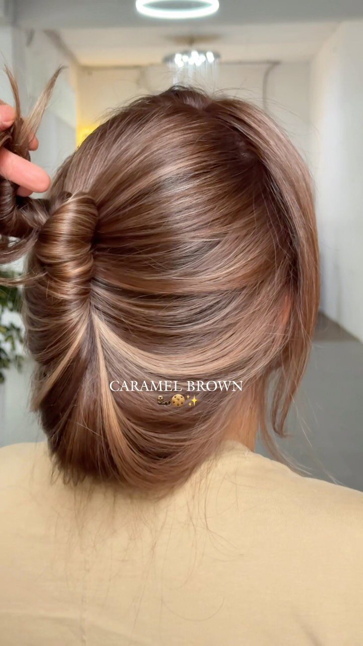 Brown updo with caramel highlights woven through the smooth twisted hairstyle