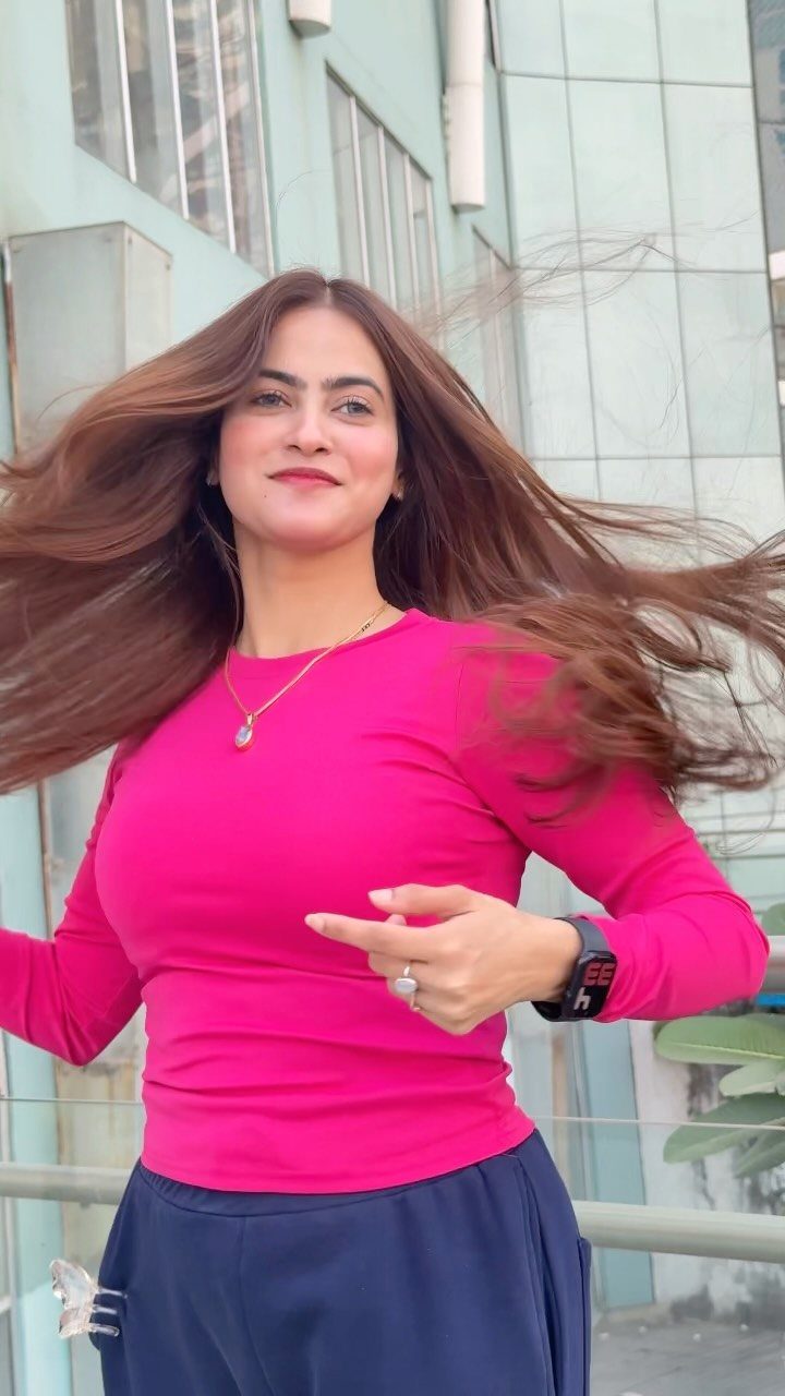 Woman with long, flowing chestnut brown hair wearing a bright pink top