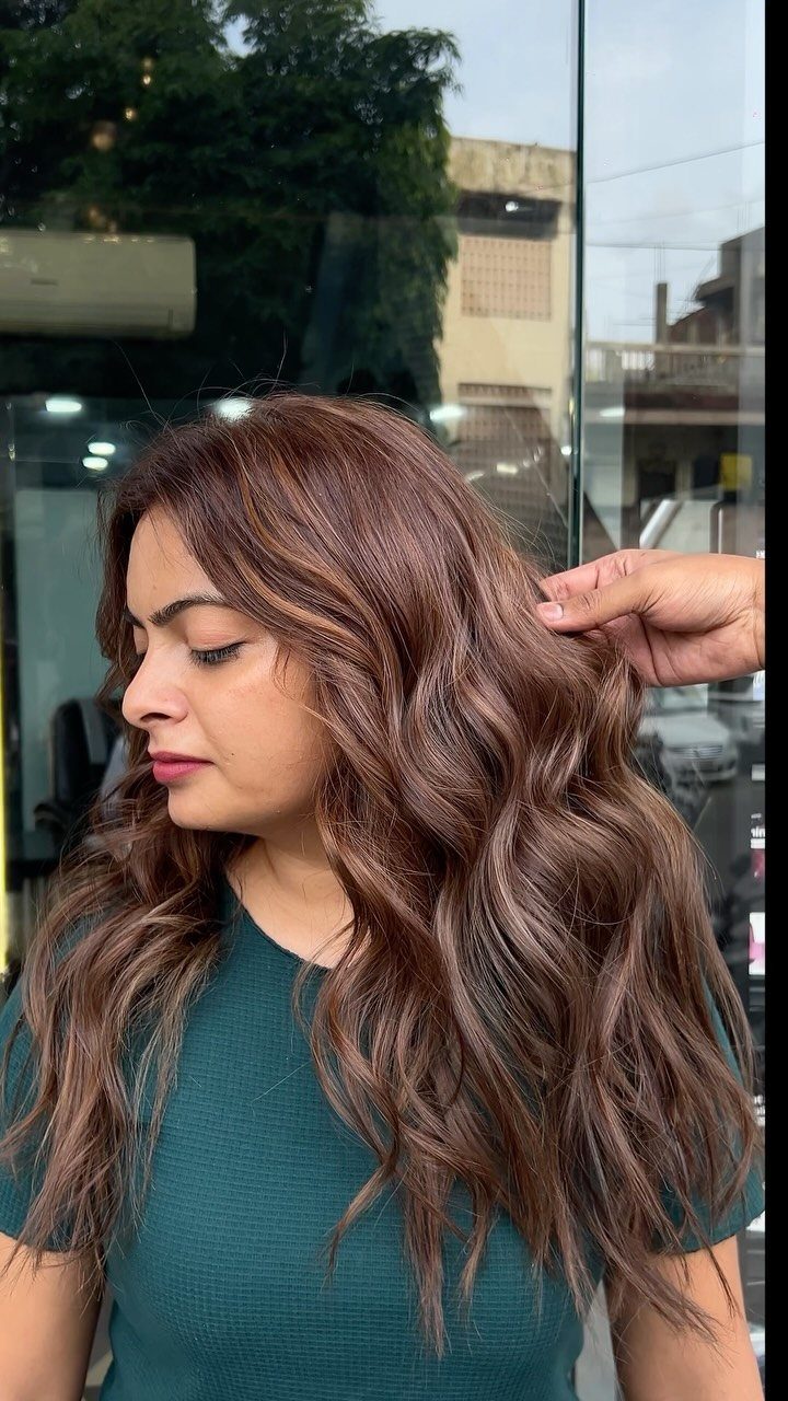 Woman with long wavy brown hair and subtle copper highlights at a salon