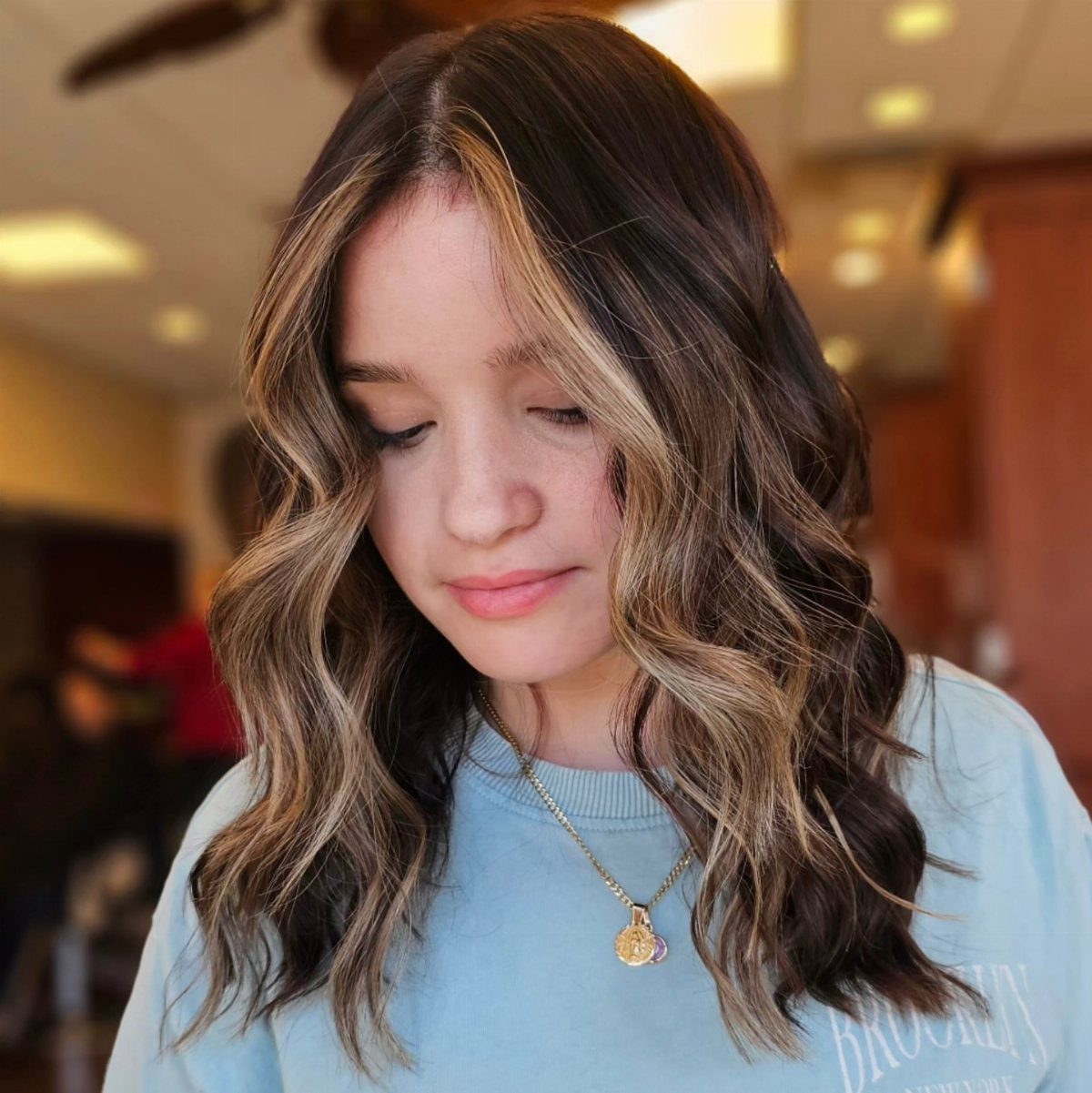 Wavy brown hair with lighter caramel pieces framing a woman's face