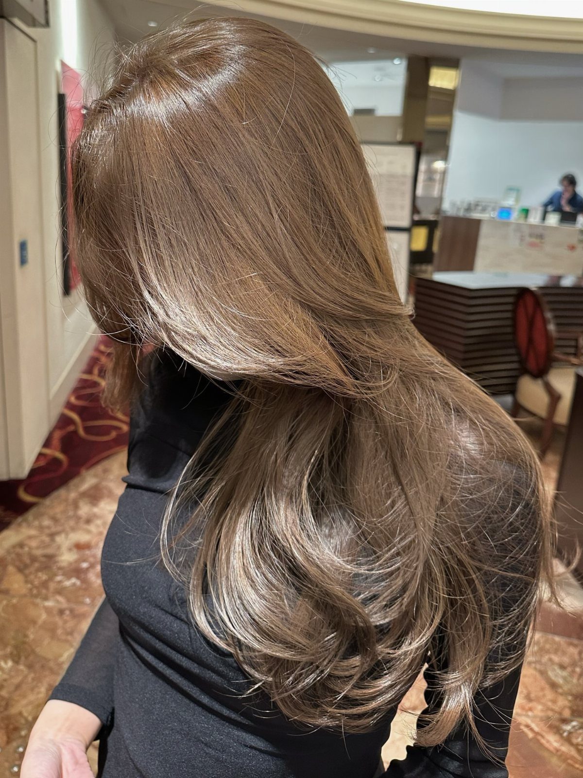 Long hazelnut brown hair styled in glossy, loose layered curls