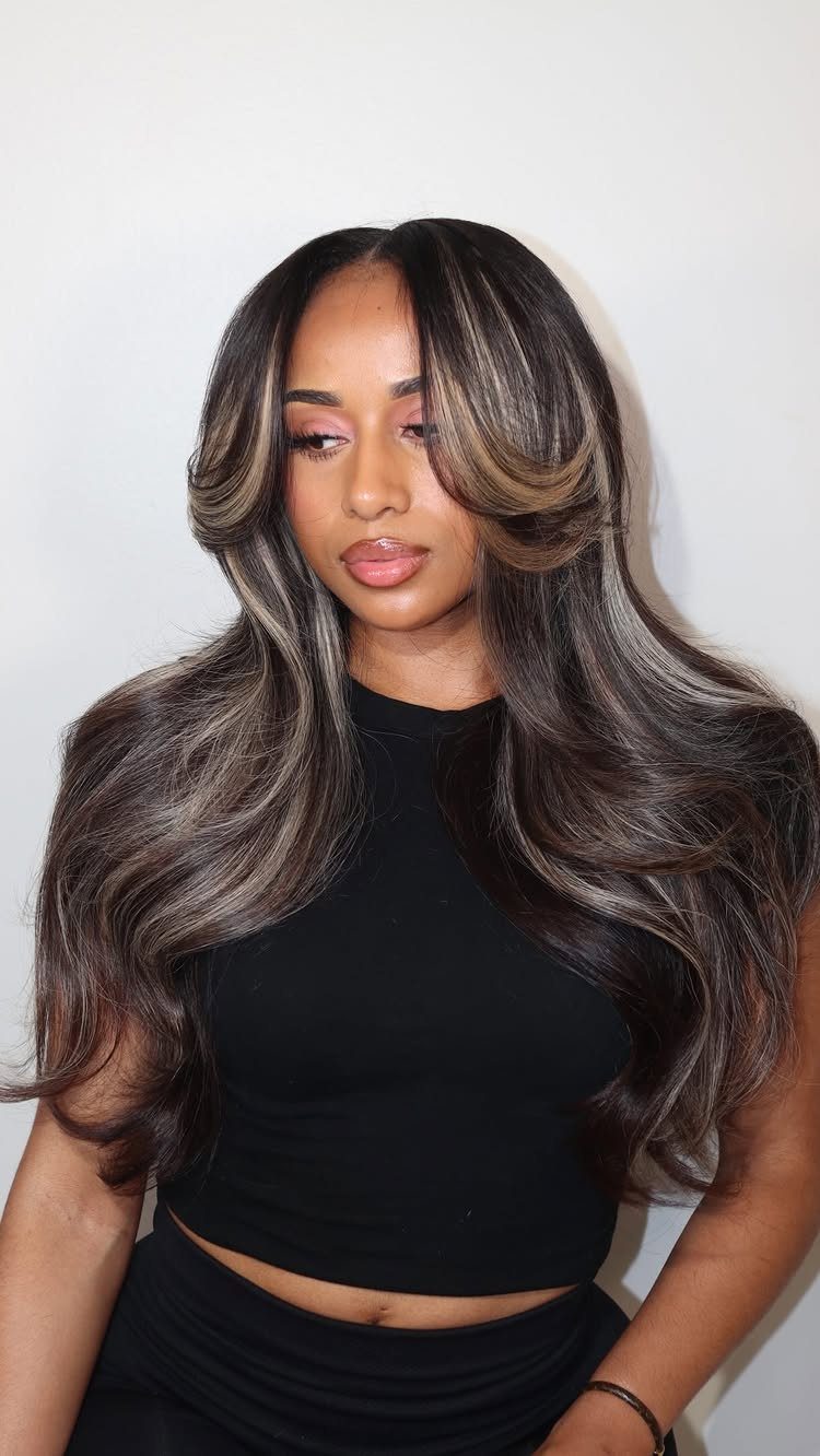 Woman with long dark brown hair and cool-toned face-framing highlights