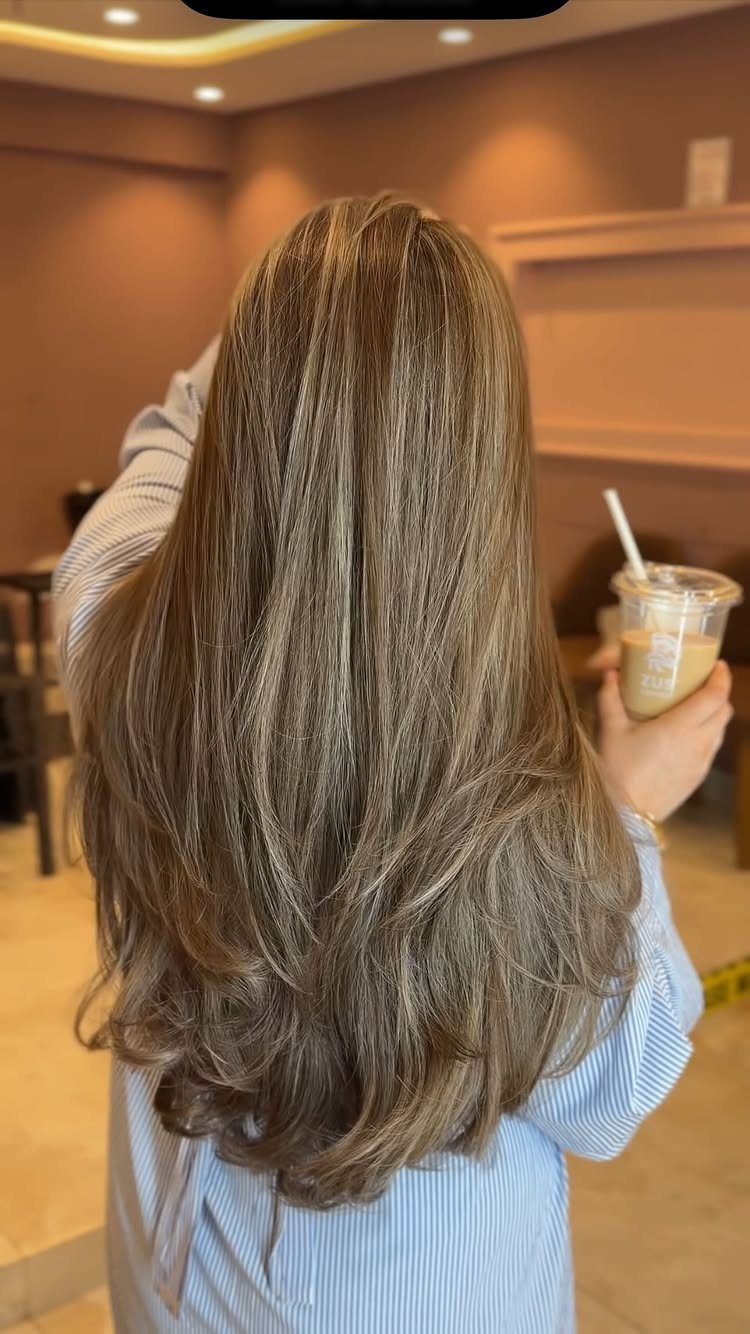 Long light brown hair falls straight down the back in soft layers