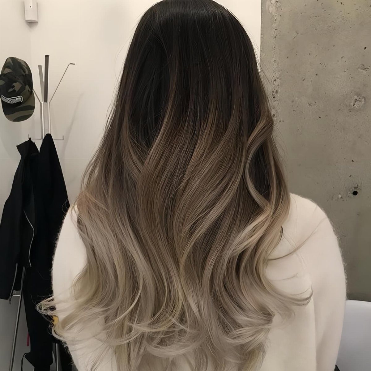 Wavy hair fades from dark brown roots to pale blonde ends