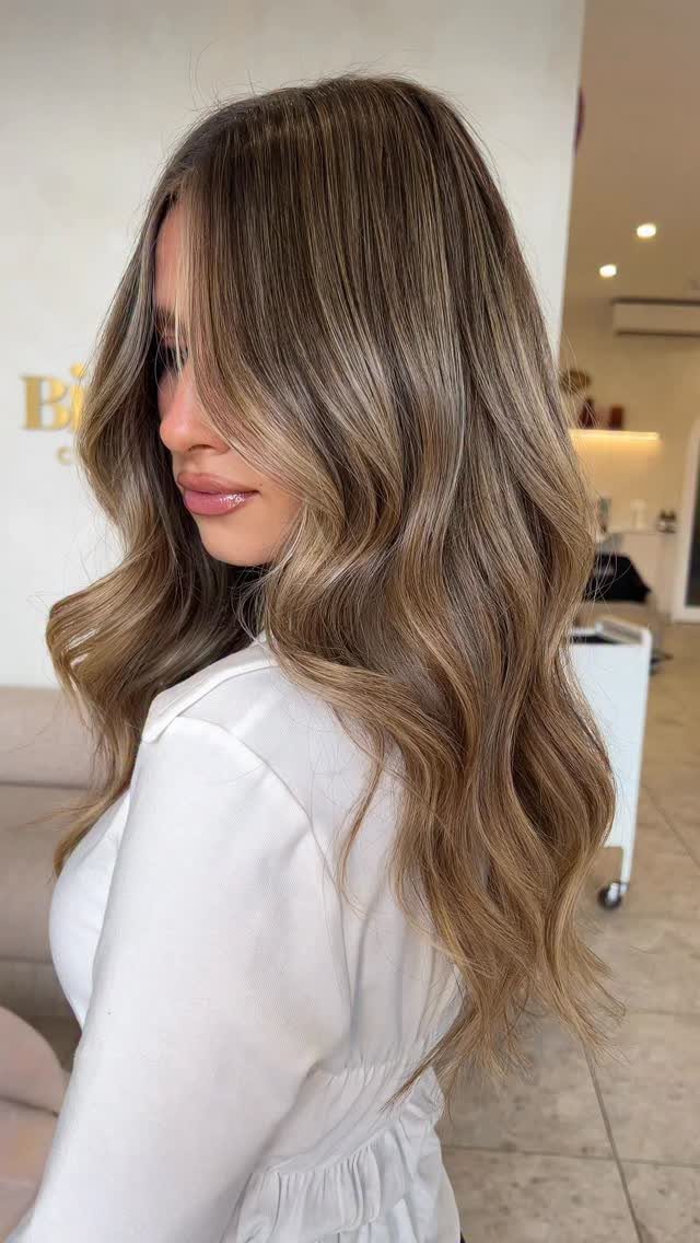 Woman with long wavy light brown hair and sunlit bronde highlights