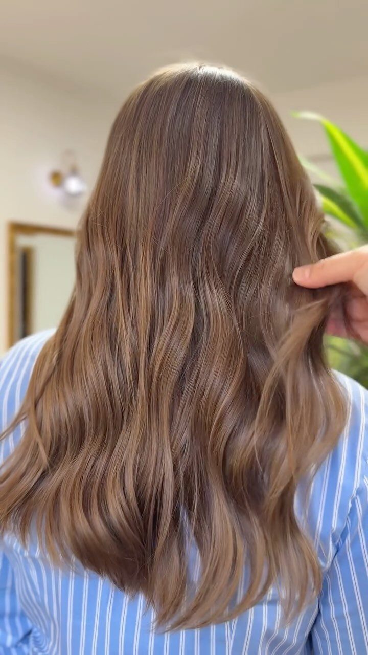 Long wavy light brown hair with subtle fine highlights and a pointing hand