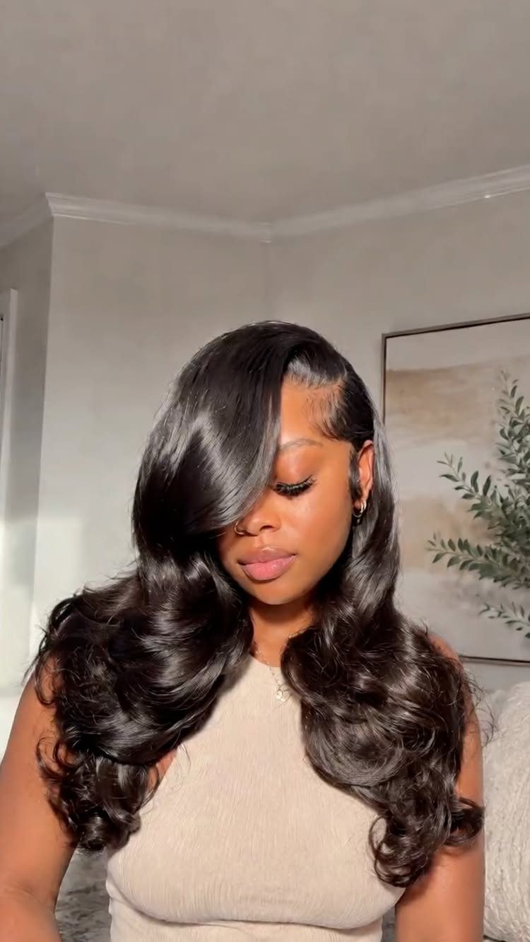 Woman wearing long, glossy black hair in voluminous waves with a deep side part