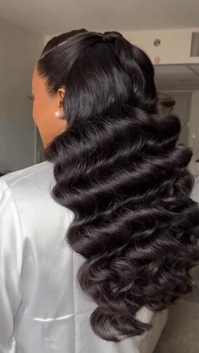 Glossy black Hollywood waves cascade down a woman’s back
