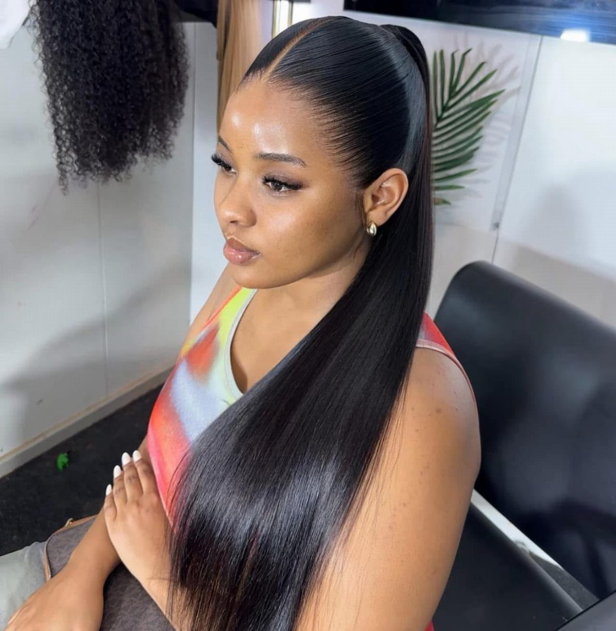 Woman wearing a sleek long straight black ponytail over her shoulder