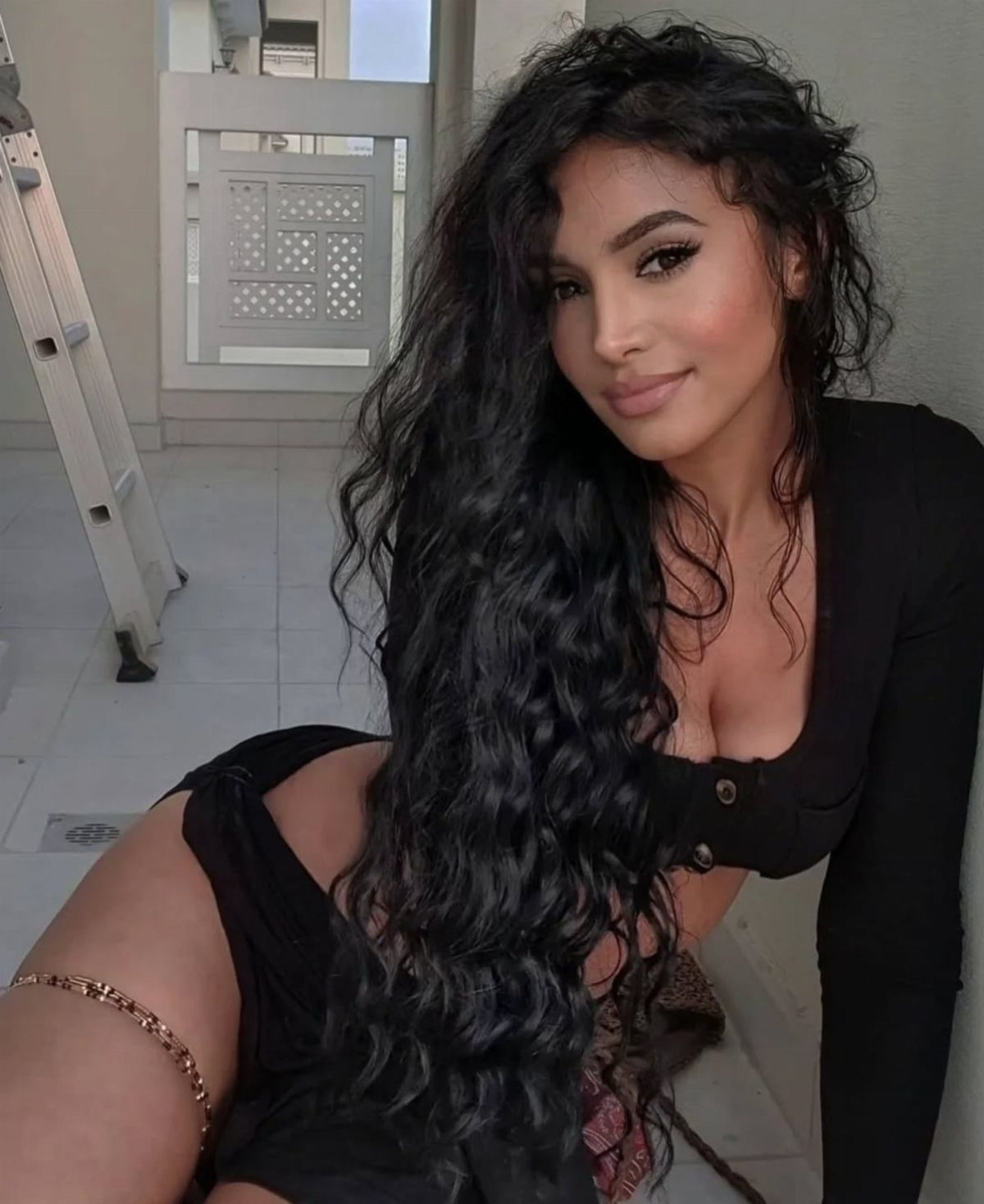 Woman posing with very long, wavy black hair falling over her black outfit