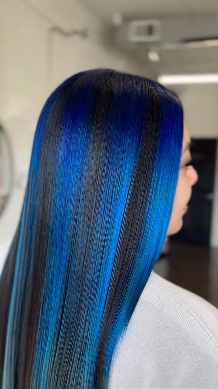Long straight black hair with vivid blue streaks falls down the person's back.