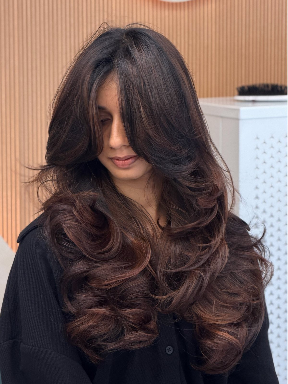 Long dark layered waves with brown highlights falling over a black top