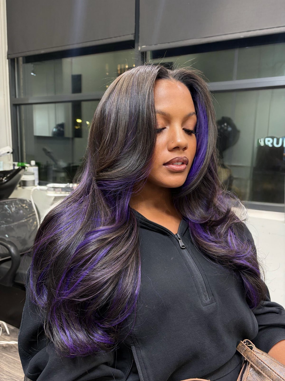 Woman with long center-parted dark waves and vivid purple streaks