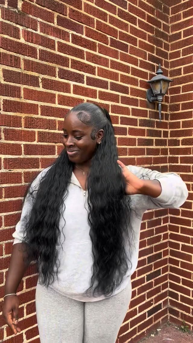 Smiling woman displays very long black hair against a red brick wall