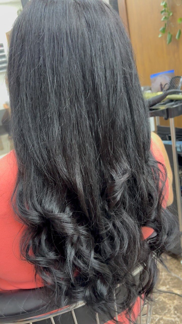 Long black hair falls straight before curling softly at the ends