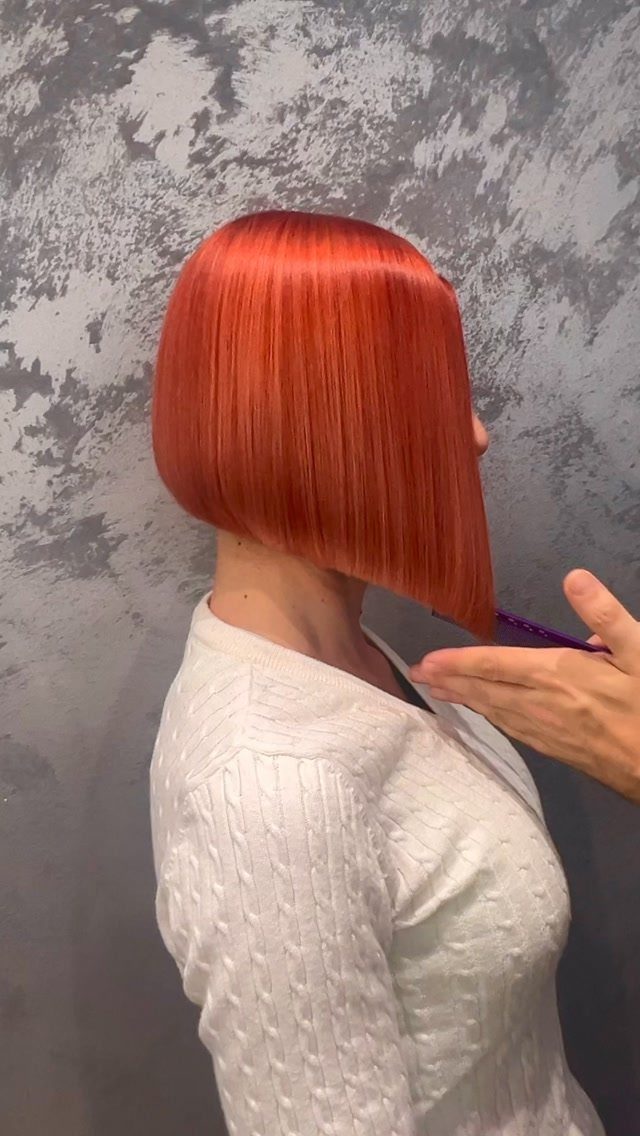 Copper-red angled bob, shorter at the back and longer in front, being trimmed