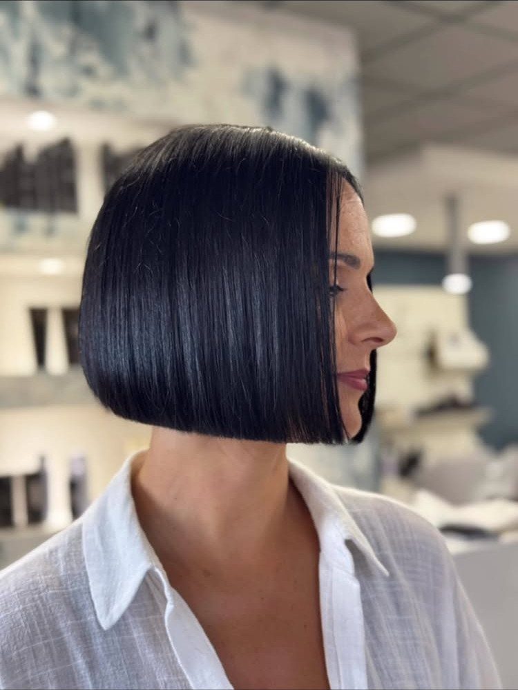 Woman showing a sleek chin-length dark bob haircut in a salon