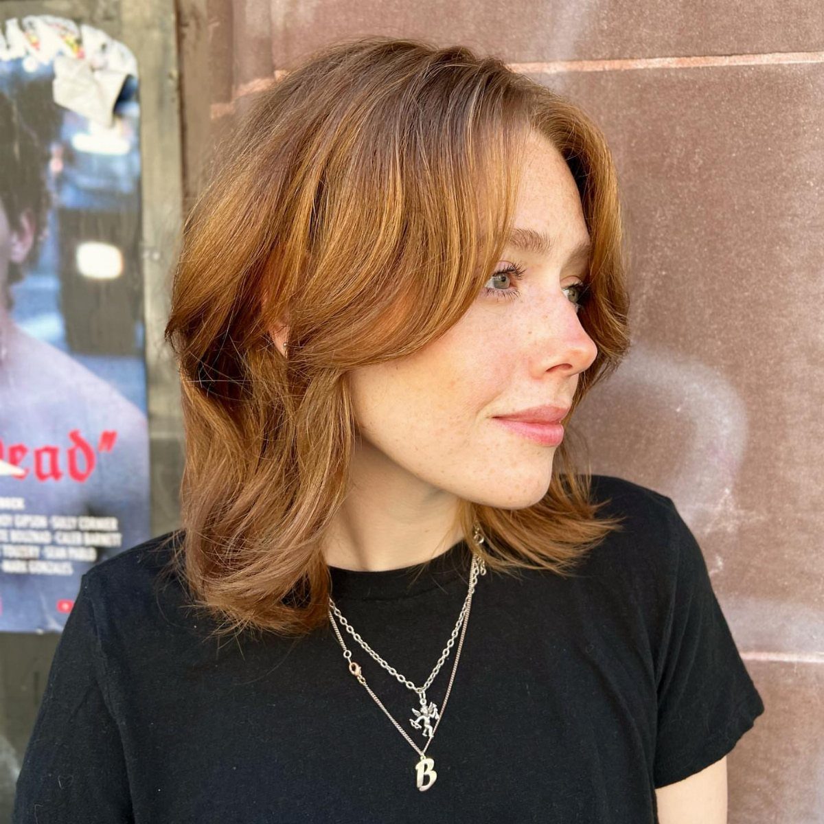Woman with a light brown layered lob and outward-flipped ends, looking to the side