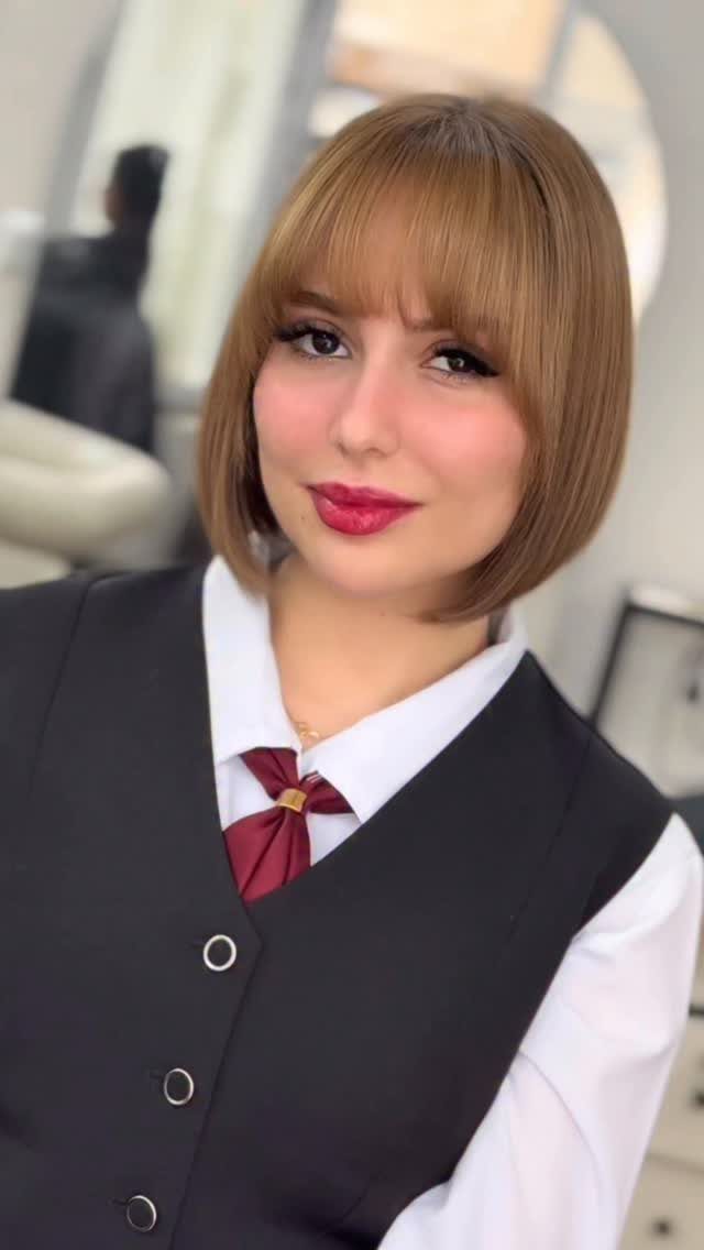 Light brown graduated bob with blunt bangs framing a person’s face