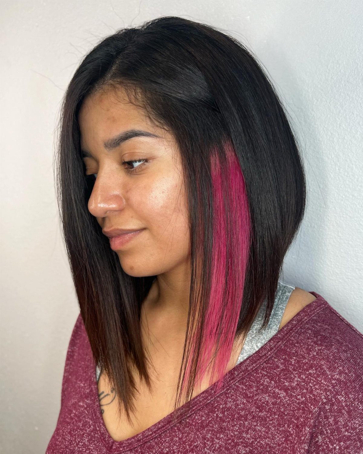 Woman showing a layered long bob with a vivid pink streak