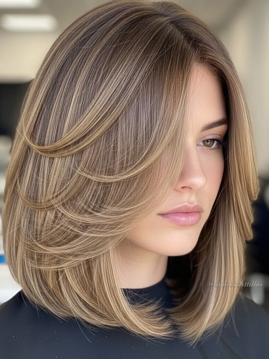 Woman wearing a highlighted, layered shoulder-length bob with softly curved ends