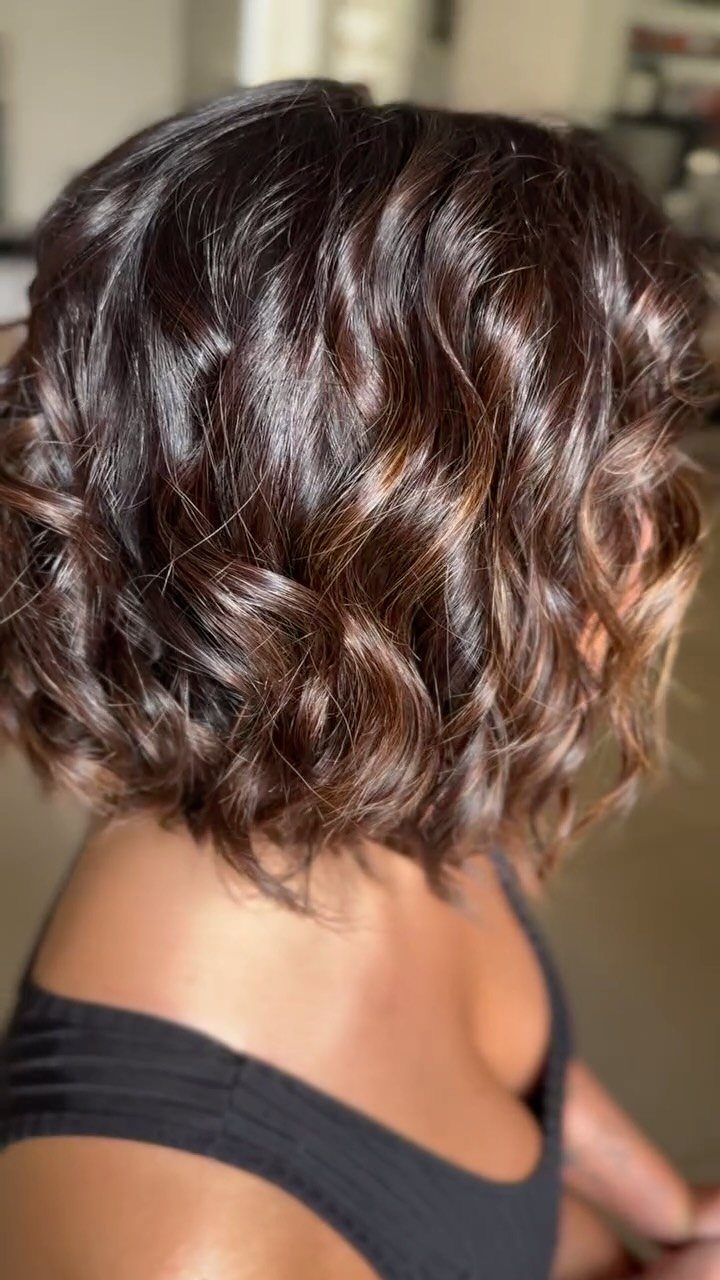 Short dark wavy bob with curls and no visible fringe