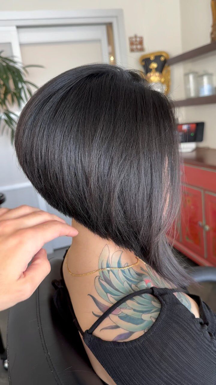 Layered dark long bob haircut with a longer front section in a salon